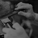 Cabeleireiro fazendo corte masculino com pente e máquina